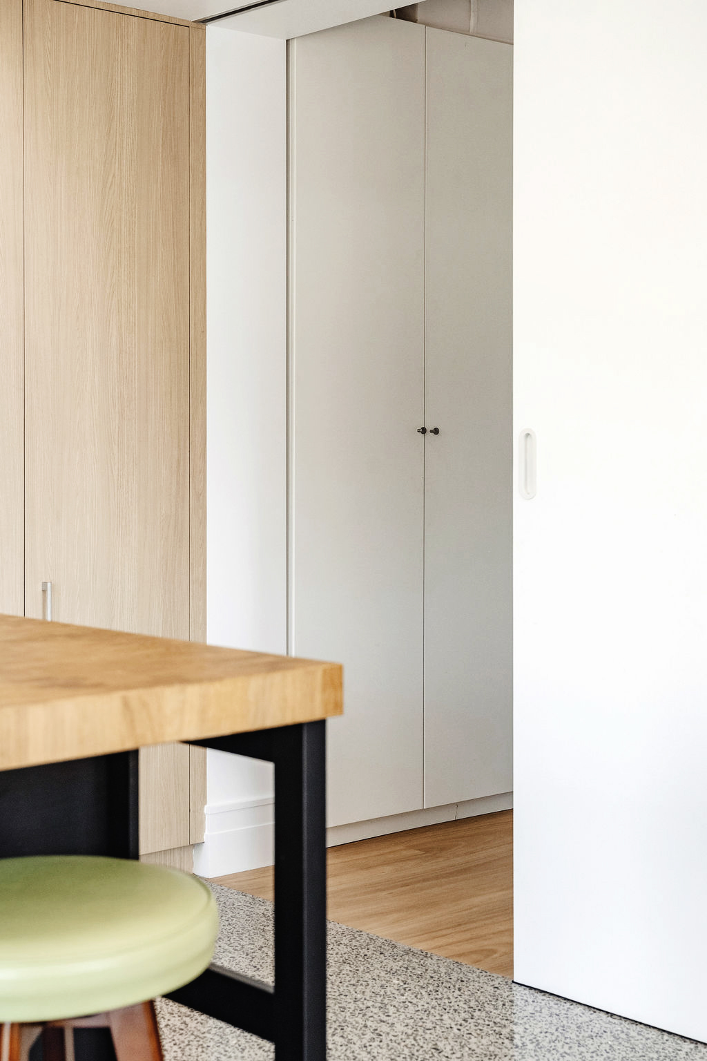 Timber bench and pale timber joinery beside white sliding door in modern interior