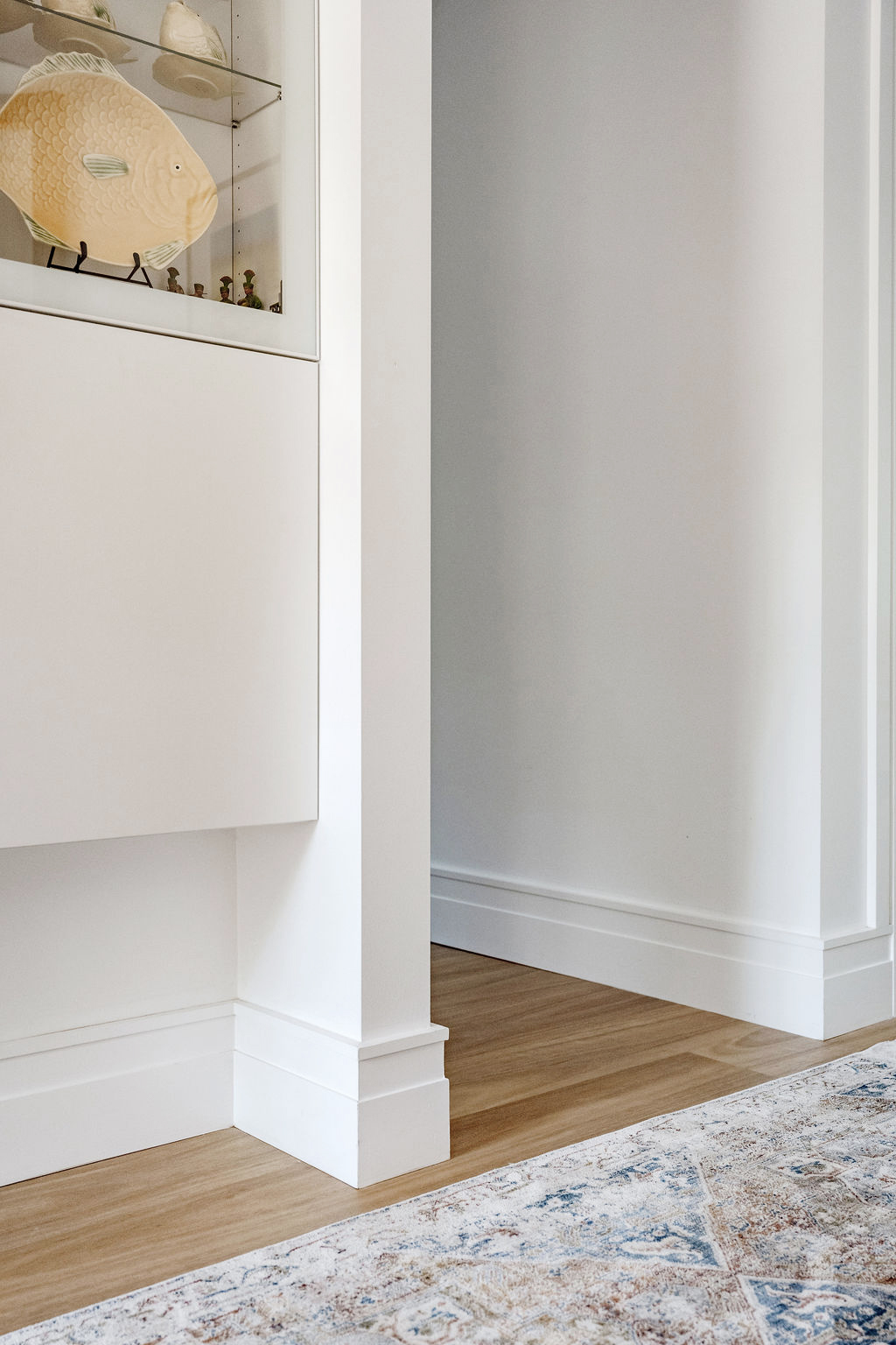 Hallway corner with white cabinetry, timber flooring and built-in display niche
