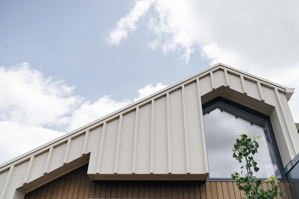 Modern gabled roof with cream vertical cladding and large geometric window